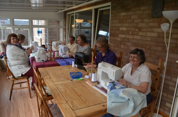A group of people around a table sewing morsbags together at a morsbagging session